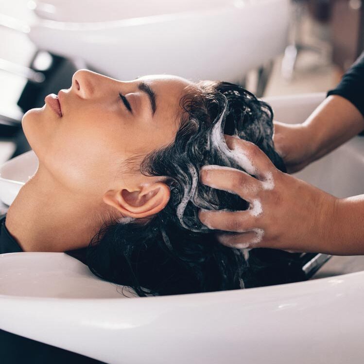 Woman getting her hair washed at shampoo bowl in a salon