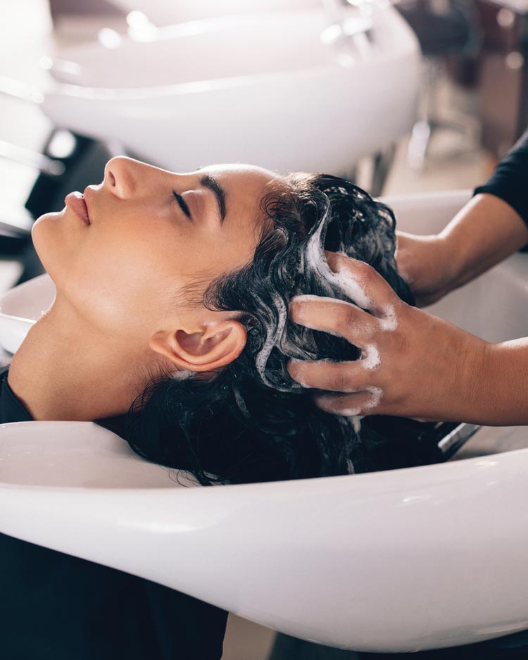 Woman getting her hair washed at shampoo bowl in a salon