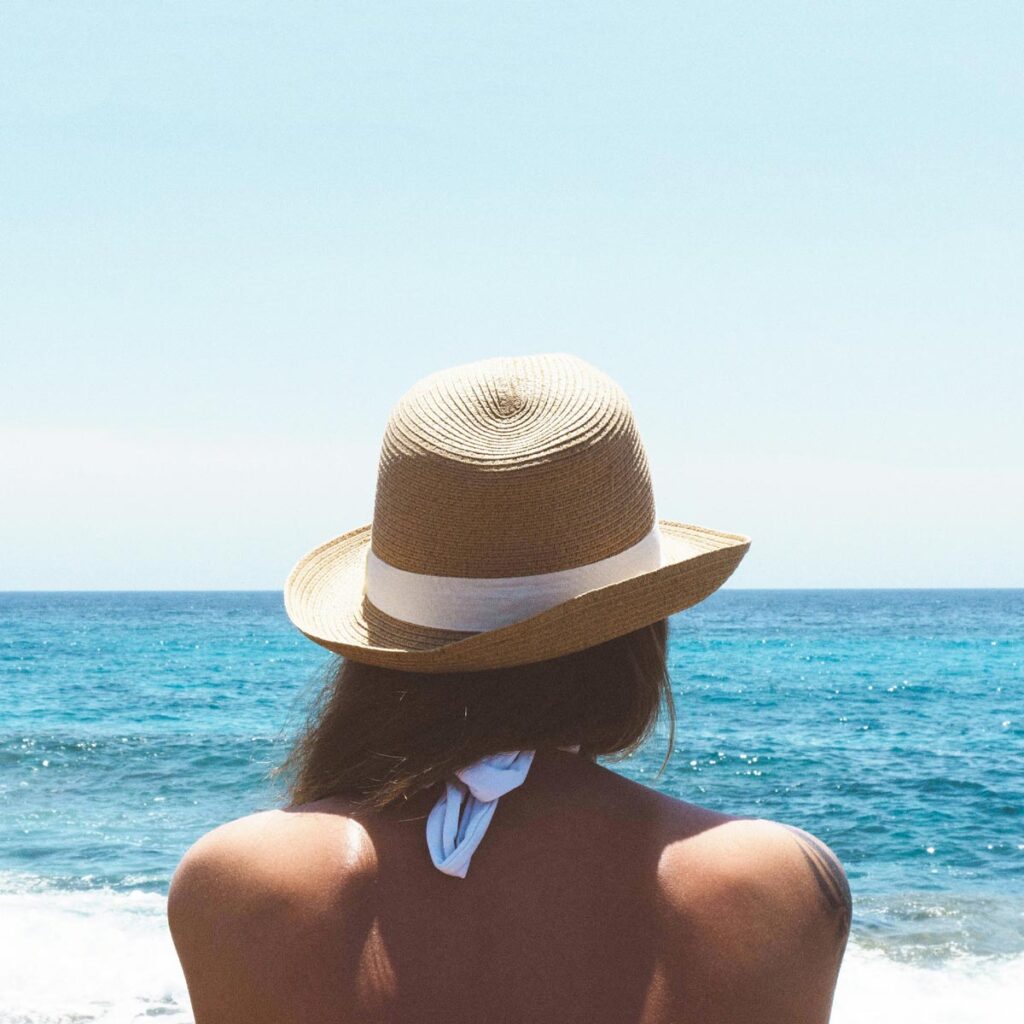 A woman at the beach with a sunhat