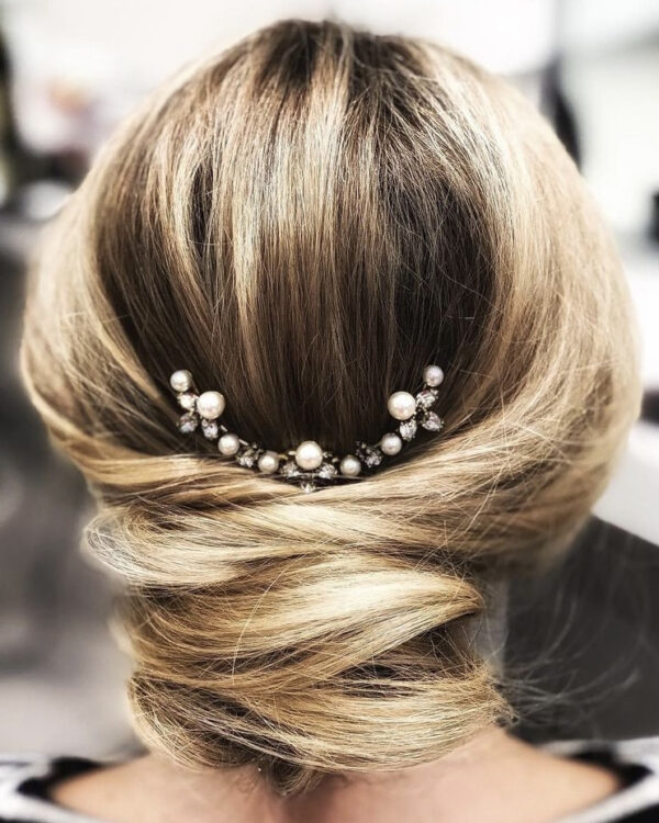 Updo with a silver and pearl hair accessory above it.